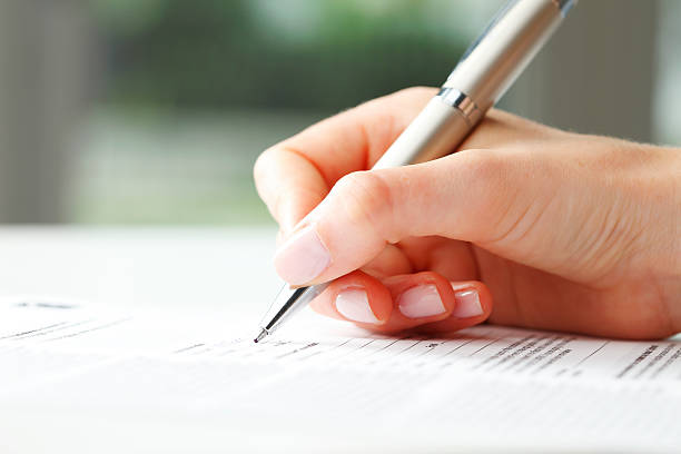 Businesswoman’s hand with pen completing personal information on a form